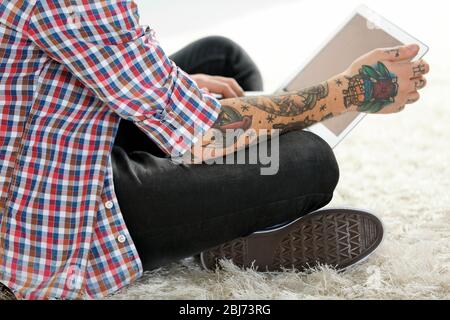 Young man with tattoo using laptop on a floor at home Stock Photo