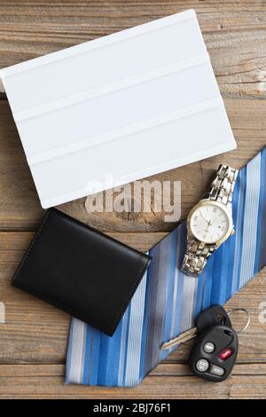 Accessories laid out on a wooden surface for a formal occasion with a white box and a watch, wallet, tie, and car keys Stock Photo