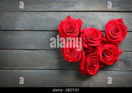 Fresh red roses buds in shape of heart on wooden background Stock Photo ...