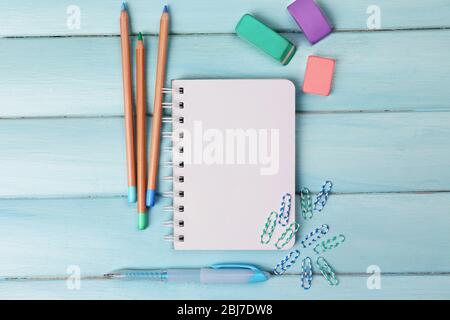 Office set with notebook, colored pencils and erasers on blue background Stock Photo