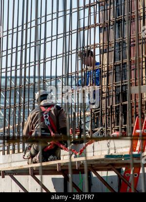 Grand rapids Michigan USA ; two workers fix re-bar grid to strengthen cement walls on a new construction building Stock Photo