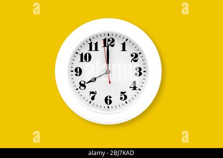 Modern wall clock white isolated on yellow background, time and period, office timepiece and mockup with hour and minute, hour hand, object classic. Stock Photo