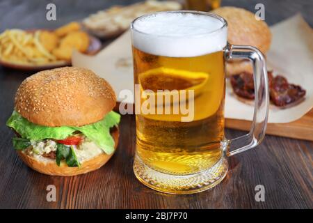 Glass mug of light beer with hamburgers on dark wooden table, close up Stock Photo