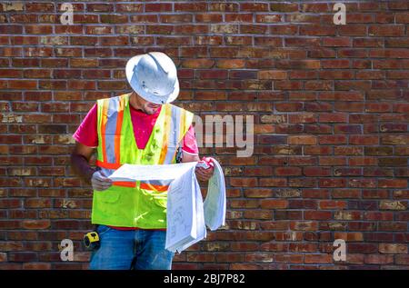 A Worker is looking at blueprints while on a job site Stock Photo