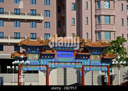 Traditional chinese archway in front of a modern building. Qianmen East Street, Beijing. China Stock Photo