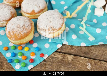 Delicious sugary donuts with blue napkin on wooden table closeup Stock Photo