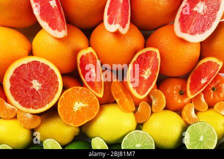 Colorful mixed citrus fruit sorted and lined up in rows with slices and halves, top view Stock Photo