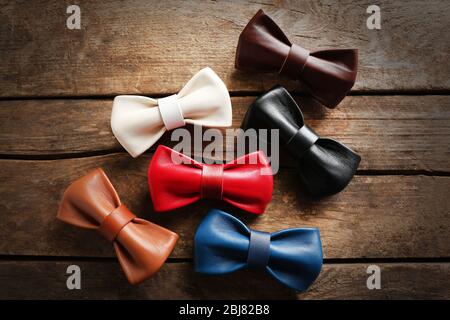 A set of colorful leather bow ties on a brown wooden background Stock Photo