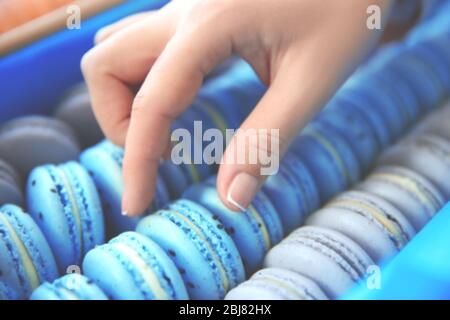 Female hand taking tasty macaroon from the box Stock Photo