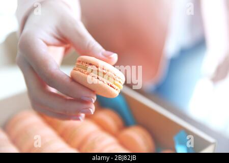 Female hand taking tasty macaroon from the box Stock Photo