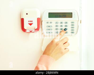Woman pressing button on security system indoors Stock Photo