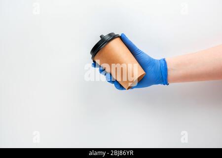 Eco Cup in hand with a glove on a white background. Coffee to go, safe distribution Stock Photo