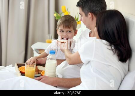 Family having breakfast with orange juice and buns in bed Stock Photo