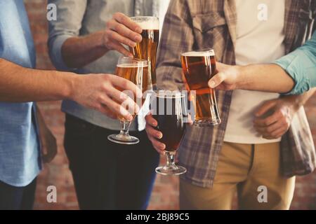 Male group clinking glasses of dark and light beer on brick wall background Stock Photo