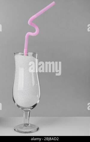 Hurricane glass with granulated sugar and cocktail straw on grey background Stock Photo