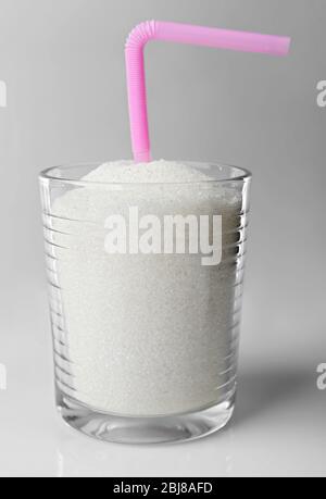 Old fashioned glass with granulated sugar and cocktail straw on grey background Stock Photo