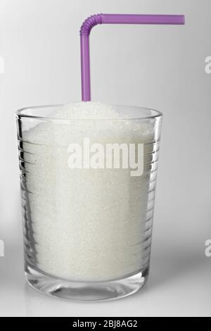 Old fashioned glass with granulated sugar and cocktail straw on grey background Stock Photo