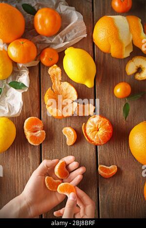 Woman holding clear mandarin and mix of citrus fruits on wooden table Stock Photo