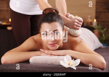 Beautiful young girl having massage with herbal balls in spa salon Stock Photo