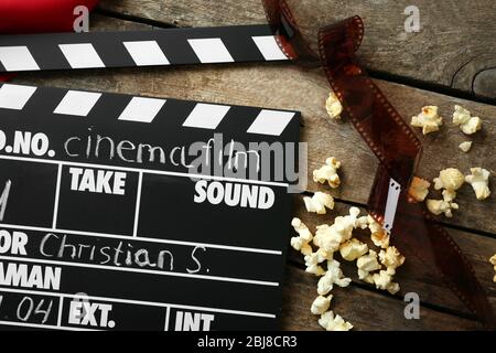Movie clapper board with popcorn on the wooden table. Stock Photo