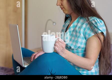 Portrait of young woman using laptop drinking coffee Stock Photo