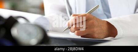 Hands of female GP making notes with silver pen Stock Photo
