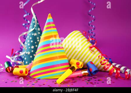 Three Birthday hats with serpentine streamer and noise makers on purple background Stock Photo