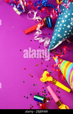 Birthday hats with serpentine streamer and noise makers on purple background Stock Photo