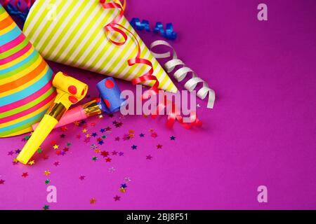 Birthday hats with serpentine streamer and noise makers on purple background Stock Photo