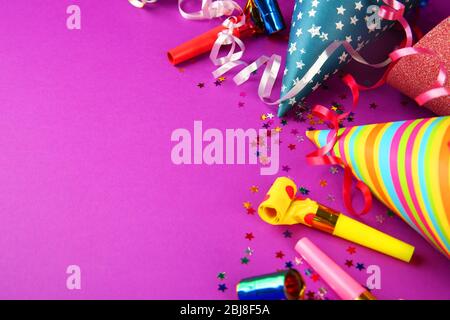 Birthday hats with serpentine streamer and noise makers on purple background Stock Photo