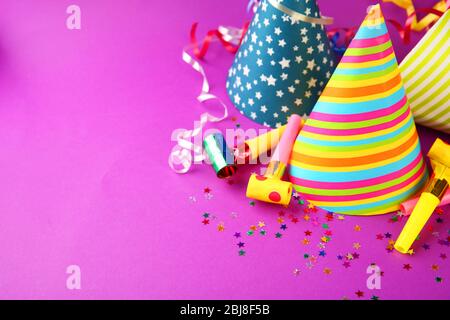 Birthday hats with serpentine streamer and noise makers on purple background Stock Photo