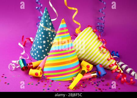 Three Birthday hats with serpentine streamer and noise makers on purple background Stock Photo