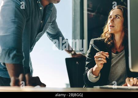 Two business partners discussing work in office. business executives working together at office desk. Stock Photo