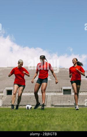 Three females playing football during team practice in field. Women soccer players playing on the sports field. Stock Photo