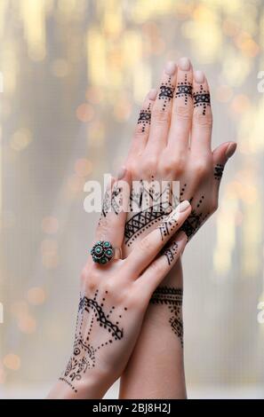 Female hands with henna tattoo on bright blurred background Stock Photo