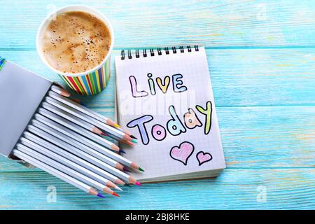 Cup of coffee with note LIVE TODAY and crayons on wooden background Stock Photo