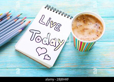 Cup of coffee with note LIVE TODAY and crayons on wooden background Stock Photo