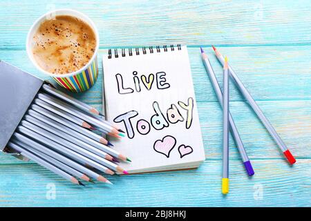 Cup of coffee with note LIVE TODAY and crayons on wooden background Stock Photo