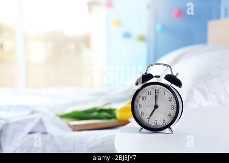 Vintage alarm clock on bedside table in a room Stock Photo
