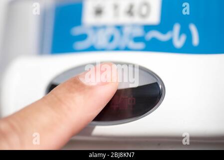 A finger pressing a button on a Japanese vending machine to buy a drink beverage. Translation: cold (drink) Stock Photo