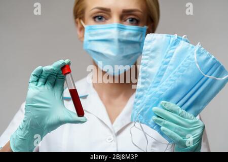 medical doctor nurse woman wearing latex gloves - holding virus blood test and protective mask Stock Photo