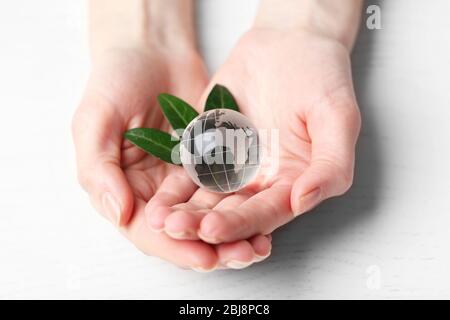 Female hands holding small glass globe over wooden table closeup Stock Photo