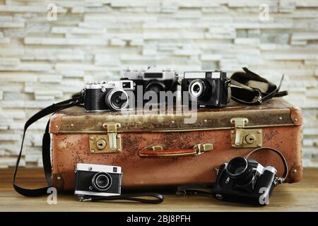 Old cameras and vintage suitcase on brick wall background Stock Photo