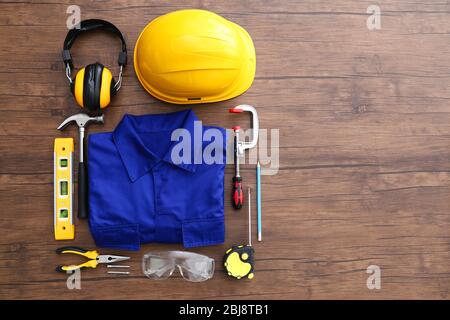 Uniform and construction tools on wooden table, top view Stock Photo