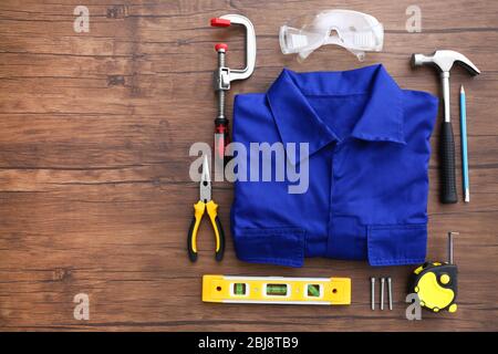 Uniform and construction tools on wooden table, top view Stock Photo