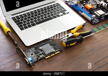 Laptop and Different electronic circuits, tools on wooden background Stock Photo