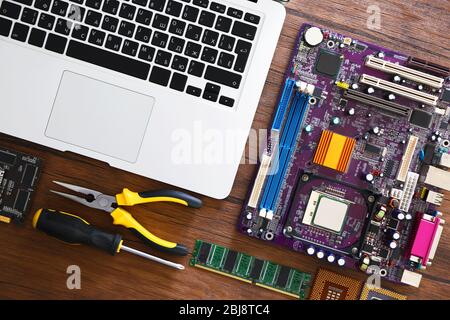 Laptop and different electronic circuits, tools on wooden table, top view Stock Photo