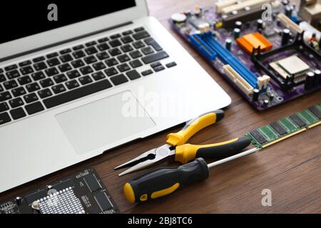 Laptop and Different electronic circuits, tools on wooden background Stock Photo