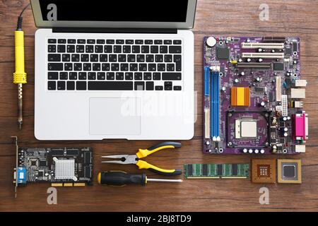 Laptop and different electronic circuits, tools on wooden table, top view Stock Photo