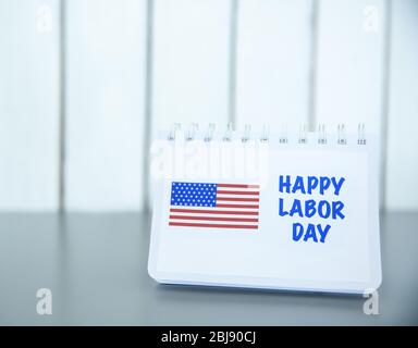 Notebook with printed text HAPPY LABOR DAY and American flag on wooden background Stock Photo